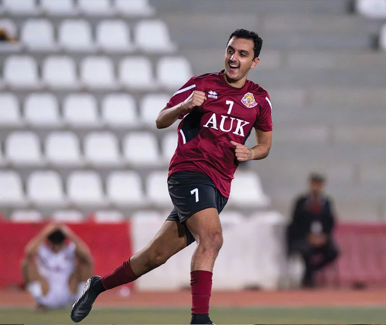 An AUK football player celebrating after scoring a goal during a thrilling match.