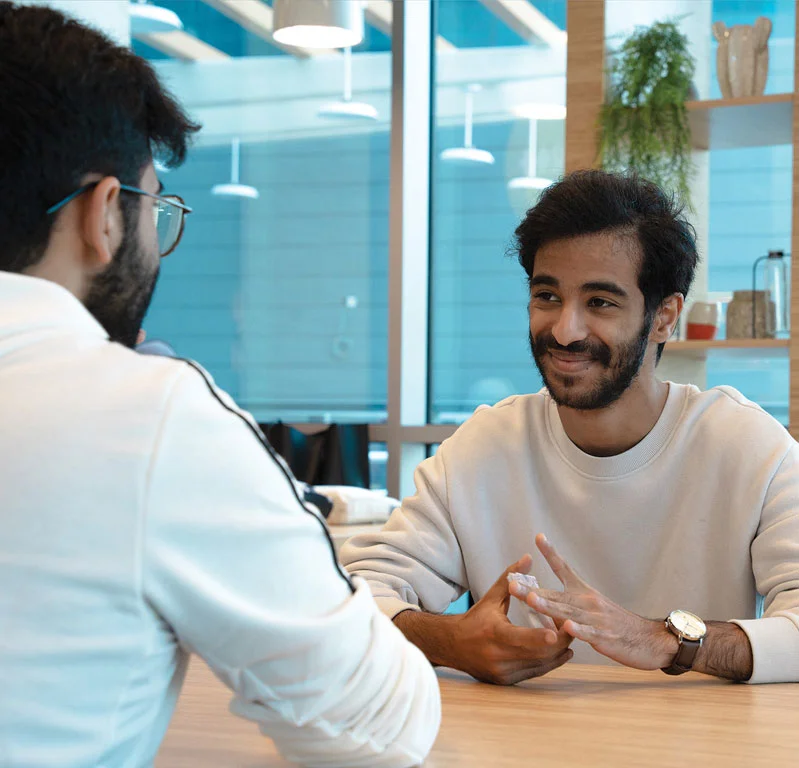 Two AUK students conversing on campus, exchanging ideas and experiences