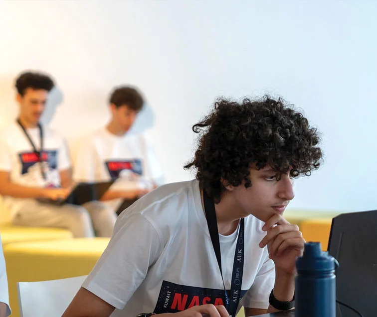 A young AUK student deep in thought, reflecting on academic insights.