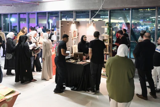 A vibrant event hosted by The American University Of Kuwait - AUK, with a group of people gathered and interacting.