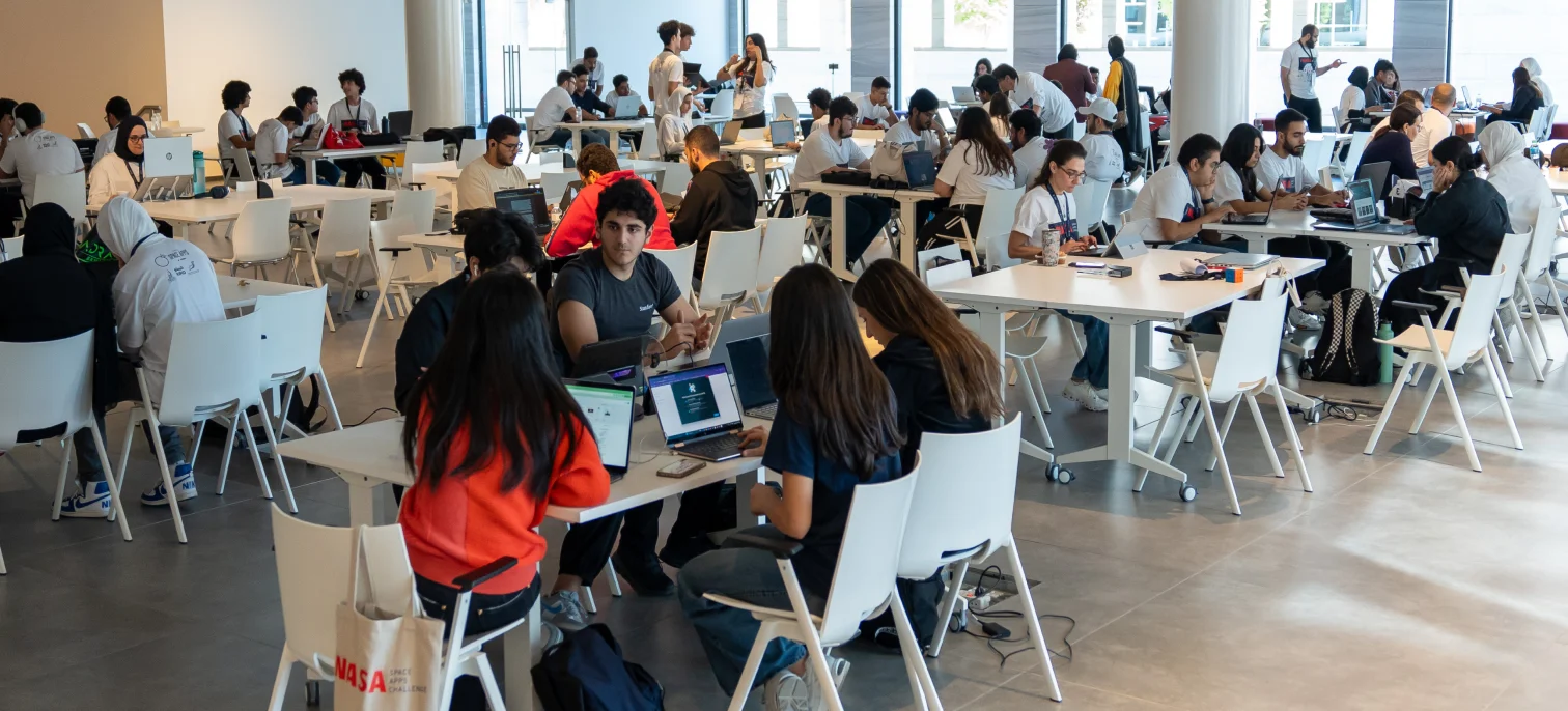 A group of AUK students seated at tables with laptops, demonstrating productivity and learning on campus.