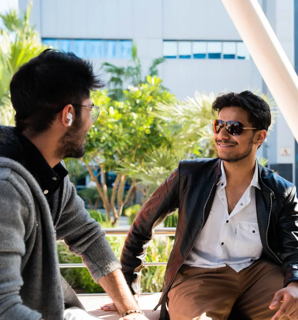 Two young students at AUK enjoying their time together on the university grounds, sharing laughter and collaboration.