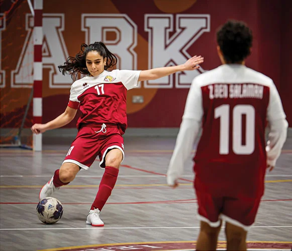 A young female AUK football player actively competing on the field.