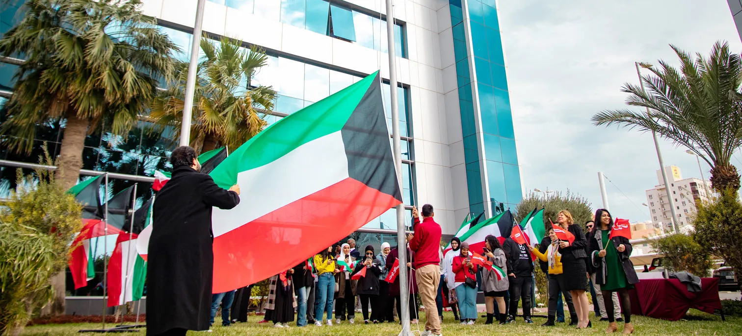 AUK students proudly raising the Kuwait flag, celebrating national pride.